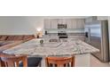 Kitchen island featuring a stainless steel sink, granite counters, seating, and stainless steel appliances in the background at 1504 Colt Creek Pl, Wesley Chapel, FL 33543