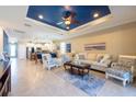 Open living room with tile floors, a tray ceiling, and comfortable seating at 16331 Treasure Point Dr, Wimauma, FL 33598