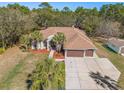 Beautiful home with a three-car garage, and a well-manicured lawn and driveway in a treed lot at 16340 Marquis Rd, Brooksville, FL 34614