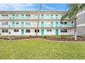 Exterior shot of multi-story condo building featuring turquoise railing, doors, and lush green lawns at 1900 59Th N Ave # 217, St Petersburg, FL 33714