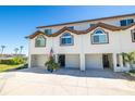 Three-story townhome featuring a private garage, manicured landscaping, arched windows, and waterfront views at 301 Madeira Cir, Tierra Verde, FL 33715