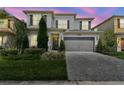 Charming two-story home with a manicured lawn, gray driveway, and a large two-car garage at 32199 Mahogany Valley Dr, Wesley Chapel, FL 33543