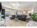 Open concept living room with a modern kitchen, large sectional sofa, sliding glass doors, and plenty of natural light at 7494 Pool Compass Loop, Wesley Chapel, FL 33545