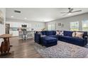 Open-concept living room with a large blue sectional sofa and adjacent kitchen at 7580 Freesia Trce, Wesley Chapel, FL 33545