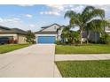 Charming two-story home featuring a blue garage door and mature landscaping at 1571 Montgomery Bell Rd, Wesley Chapel, FL 33543
