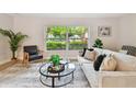 Cozy living room featuring a comfortable sofa, area rug, and a view of the lush greenery outside at 1870 Wateroak W Dr, Clearwater, FL 33764