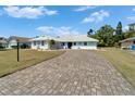 Inviting single-story home featuring a well-manicured lawn and brick paver driveway at 1929 New Bedford Dr, Sun City Center, FL 33573