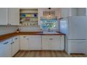 Well-lit kitchen with white cabinets, wooden countertops, modern appliances, and a view from the window at 2700 Bayshore Blvd # 1E, Dunedin, FL 34698