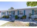 Charming home featuring a light-gray brick exterior with striking blue shutters and a beautifully landscaped front yard at 6712 W Clifton St, Tampa, FL 33634