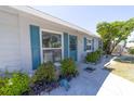 Charming home featuring a light-gray brick exterior with striking blue shutters and a beautifully landscaped front yard at 6712 W Clifton St, Tampa, FL 33634