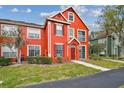 Beautiful red two-story townhome with lush green lawn and blue skies creating a picturesque, appealing exterior at 9118 Lake Chase Island Way # 9118, Tampa, FL 33626