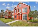 Beautiful red two-story townhome with lush green lawn and blue skies creating a picturesque, appealing exterior at 9118 Lake Chase Island Way # 9118, Tampa, FL 33626
