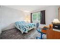 Bright bedroom with a patterned bedspread, wood floors, and a large window at 13102 Wagner Dr, Hudson, FL 34667