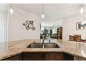 Stylish kitchen island with granite countertops, a stainless steel sink, and pendant lighting, creating a chef-friendly space at 32853 Woodthrush Way, Wesley Chapel, FL 33545