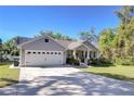 Home with an attached two-car garage and front porch with beautiful landscaping at 37362 Dixie Ave, Dade City, FL 33525