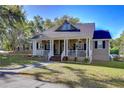 Inviting home featuring a classic front porch, showcasing a well-kept lawn and mature trees on a sunny day at 37410 Dixie Ave, Dade City, FL 33525