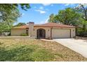 Front view of a charming home with a two-car garage, arched entryway, and well-kept lawn at 5140 Kirkwood Ave, Spring Hill, FL 34608