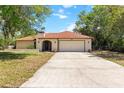 Picture of a house with a large driveway, two-car garage, arched entryway and neutral color at 5140 Kirkwood Ave, Spring Hill, FL 34608