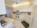 Well-lit kitchen featuring tile floors, white appliances, and ample cabinet space for storage at 6020 Shore S Blvd # 902, Gulfport, FL 33707