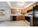 A compact kitchen featuring wood cabinets, an electric range, and black appliances at 8445 Calais N, Pinellas Park, FL 33781