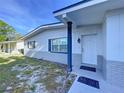 Inviting home exterior showcasing a well-kept lawn and covered entryway with dark shutters at 910 Lakeside Dr, Largo, FL 33778