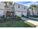 Two-story townhome exterior featuring an attached garage, lush landscaping, and a charming entrance at 1010 Mango Ct, Oldsmar, FL 34677