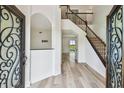 Bright foyer with wood floors, a staircase with dark wood railings, and a view of the pool through the doorway at 16323 Muirfield Dr, Odessa, FL 33556