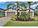 Inviting home with a well-kept lawn, mature palm trees, brick-paved driveway, and an attached two-car garage at 19611 Cypress Bridge Dr, Odessa, FL 33556