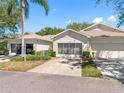 A view of the front exteriors of these attached villa-style homes, with garage, driveway, and tropical landscaping at 2618 Newcomb Ct # 12, Sun City Center, FL 33573