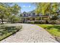 Paver driveway leading to a two-story home, framed by mature trees and manicured landscaping at 3010 82Nd N Way, St Petersburg, FL 33710