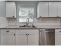Close-up of the stainless steel dishwasher, granite counters, and clean white cabinets at 3451 Pine St, Dunedin, FL 34698