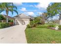 Charming home with a two-car garage, lush green lawn, and colorful landscaping at 4811 Forest Creek Trl, Parrish, FL 34219