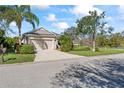 View of the home featuring a two-car garage, well-maintained lawn, and mature trees at 4811 Forest Creek Trl, Parrish, FL 34219
