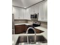 Well-lit kitchen boasting modern stainless steel appliances, white cabinetry, and double sink at 500 New York Ave # 21, Dunedin, FL 34698