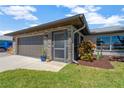 Close up of the garage, showcasing its brick accents, landscaping, and a screen door at 7094 Kenwood Dr, North Port, FL 34287