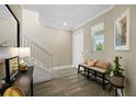 Bright foyer with a staircase, tiled floors, and a bench, creating a welcoming entrance at 8609 Winning Fields Rd, New Port Richey, FL 34655