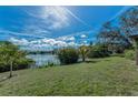Scenic backyard featuring a serene lake view, lush green grass, and mature trees on a sunny day at 1032 Jambalana Dr, Holiday, FL 34691