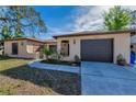 Inviting front of a single-story home with a two-car garage, well-manicured lawn, and a paved walkway at 1032 Jambalana Dr, Holiday, FL 34691