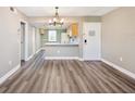 Open living and dining area features a kitchen view, gray walls, wood floors, and a modern chandelier at 106 Meadow Ln # 106, Oldsmar, FL 34677