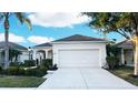 Charming single-story home showcasing a well-maintained lawn, manicured shrubbery, and an attached two-car garage at 11822 Crawford Parrish Ln, Parrish, FL 34219