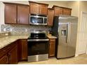 Well-equipped kitchen features granite countertops, stainless steel appliances and brown cabinets at 1706 Trailwater St, Ruskin, FL 33570