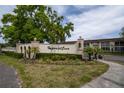 View of the Imperial Cove entrance sign, framed by lush landscaping and mature trees at 19029 Us Highway 19 N # 2-12, Clearwater, FL 33764