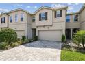 Inviting townhome with a paver driveway, attached garage, manicured lawn, and neutral exterior paint at 19398 Great Intention Way, Lutz, FL 33558