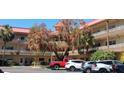 Exterior view of the building featuring balconies and lush trees in front at 2402 Ecuadorian Way # 20, Clearwater, FL 33763