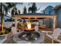Backyard features a fire pit surrounded by chairs under a covered structure with an outdoor kitchen and seating area at 3006 W Angeles St, Tampa, FL 33629