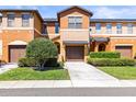 Two-story townhouse with a one car garage and front yard with a trimmed shrub at 30103 Mossbank Dr, Wesley Chapel, FL 33543