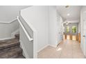 Hallway with carpeted stairs, tile flooring, and an open doorway to the living room at 30103 Mossbank Dr, Wesley Chapel, FL 33543