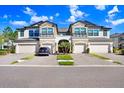 Attractive two-story townhome with a two-car garage, brick driveway, and manicured landscaping at 30300 Southwell Ln, Wesley Chapel, FL 33543