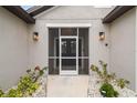 Close up of the home's screened entryway with decorative lanterns and a well kept garden at 4307 Dristol Ave, Spring Hill, FL 34609