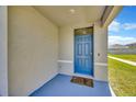 Cozy front porch with a blue front door, concrete flooring, and painted walls at 5758 Hollingworth Trl, Wesley Chapel, FL 33545